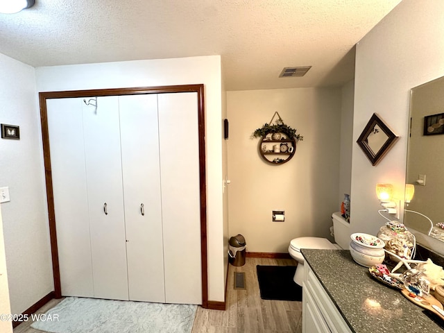bathroom with baseboards, visible vents, wood finished floors, and a textured ceiling