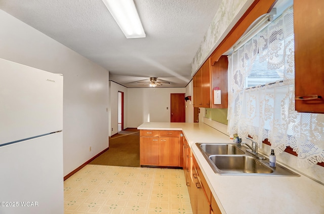 kitchen featuring sink, white fridge, ceiling fan, kitchen peninsula, and a textured ceiling