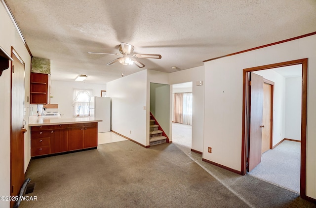 kitchen with a textured ceiling, kitchen peninsula, white fridge, ceiling fan, and carpet