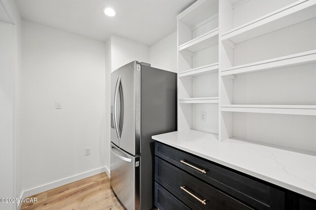 3485 Sugar Creek Rd, Lima, OH 45807 - kitchen with stainless steel fridge with ice dispenser, dark cabinetry, open shelves, light wood-style floors, and light stone counters