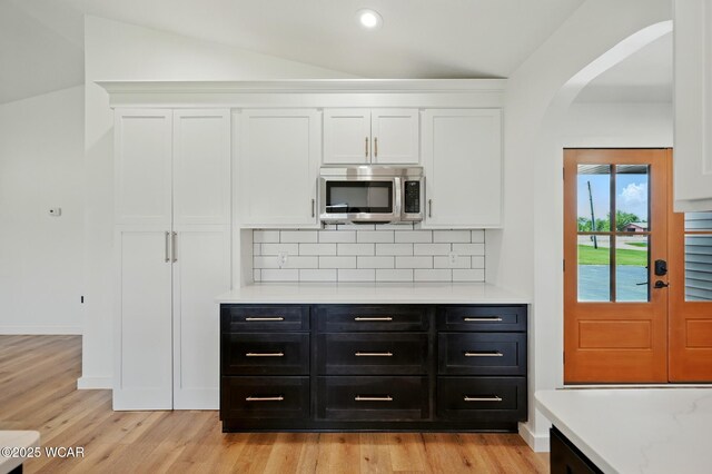 3485 Sugar Creek Rd, Lima, OH 45807 - kitchen featuring stainless steel microwave, white cabinetry, dark cabinetry, light countertops, and lofted ceiling