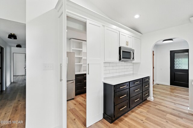 3485 Sugar Creek Rd, Lima, OH 45807 - kitchen featuring appliances with stainless steel finishes, white cabinetry, arched walkways, light countertops, and light wood finished floors