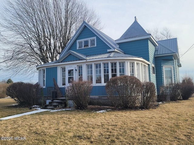 view of front of home with metal roof and a front lawn