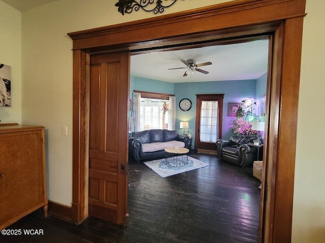 living area with ceiling fan, baseboards, and dark wood finished floors