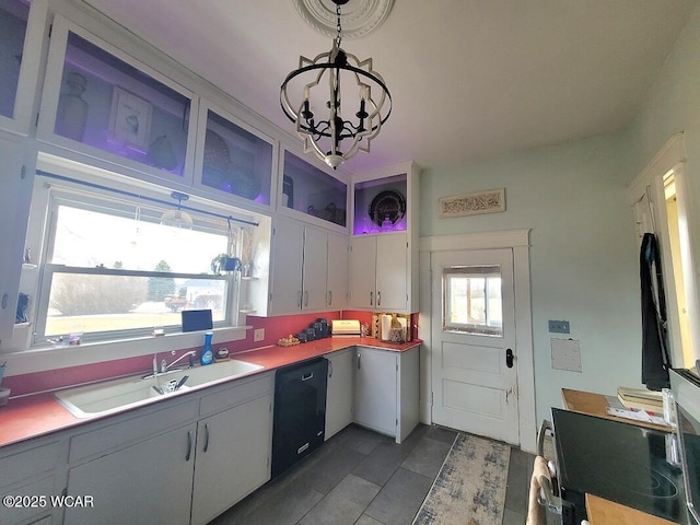 kitchen featuring a sink, white cabinets, black dishwasher, light countertops, and decorative light fixtures