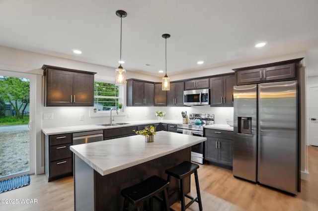 1501 W Spring St, Lima, OH 45805 - kitchen featuring appliances with stainless steel finishes, a sink, dark brown cabinetry, light wood-type flooring, and a center island