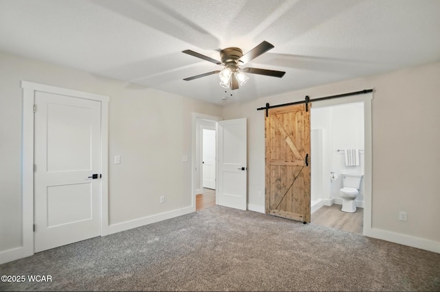 1501 W Spring St, Lima, OH 45805 - unfurnished bedroom featuring carpet, a barn door, baseboards, ensuite bath, and a ceiling fan
