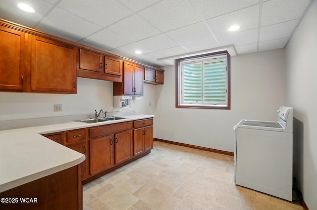 kitchen featuring brown cabinets, light countertops, washer / clothes dryer, and a sink