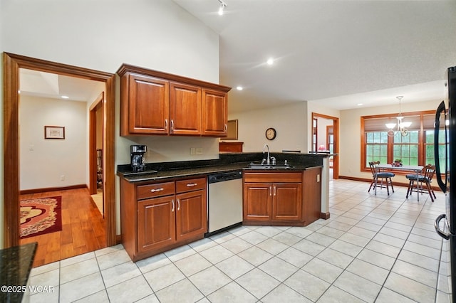 kitchen featuring a notable chandelier, dishwasher, brown cabinetry, a sink, and a peninsula