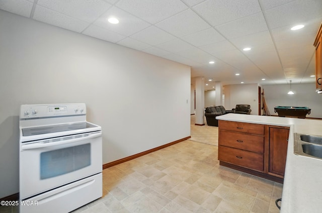kitchen featuring brown cabinetry, pool table, light countertops, white electric range, and baseboards