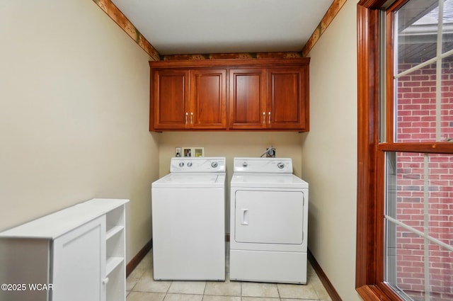 laundry room with washing machine and clothes dryer, baseboards, light tile patterned floors, and cabinet space