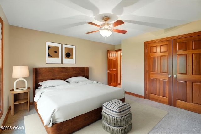 bedroom with a closet, light carpet, baseboards, and ceiling fan