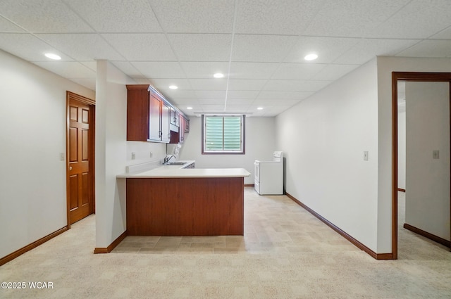 kitchen with a peninsula, light carpet, washer / clothes dryer, and a sink