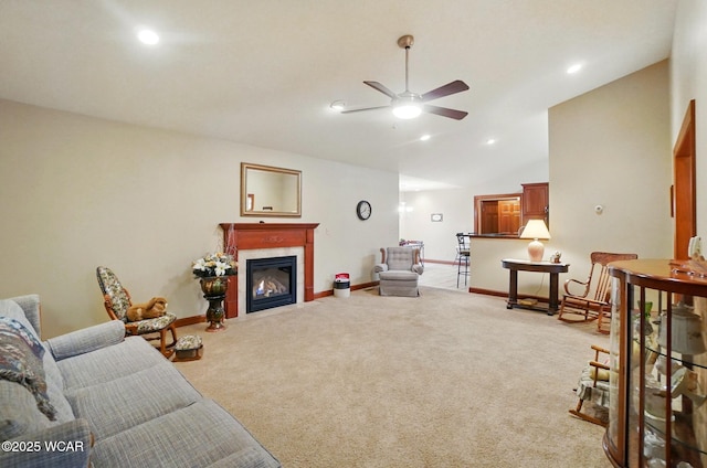 living room featuring lofted ceiling, baseboards, a glass covered fireplace, ceiling fan, and light colored carpet