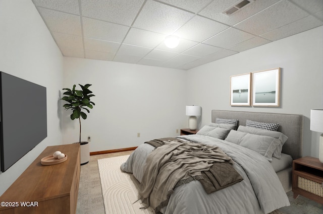 bedroom with carpet floors, baseboards, visible vents, and a drop ceiling