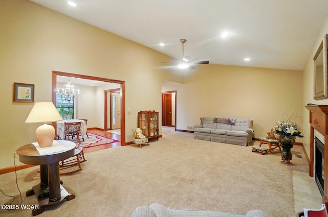 carpeted living room with baseboards, ceiling fan with notable chandelier, a fireplace with flush hearth, and recessed lighting