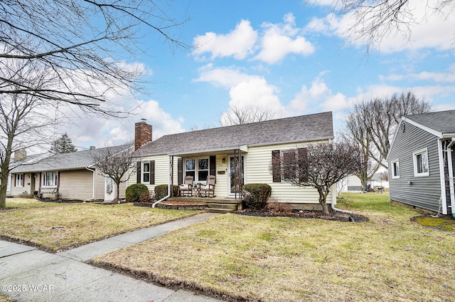 ranch-style house with roof with shingles, a porch, a chimney, and a front yard