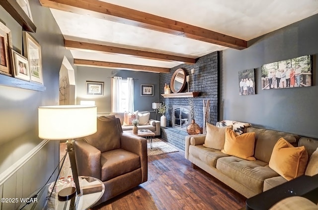 living room featuring dark wood-style flooring, a fireplace, and beamed ceiling