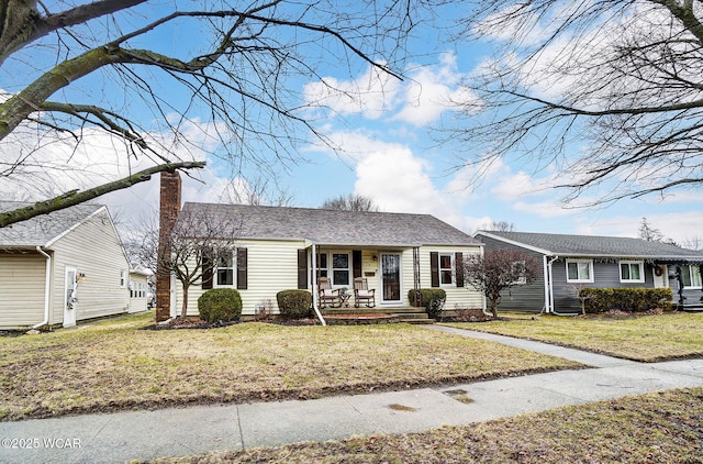 ranch-style home with a porch, a chimney, and a front lawn