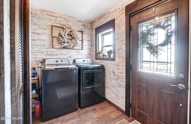 laundry area with laundry area, wood finished floors, washing machine and clothes dryer, and baseboards