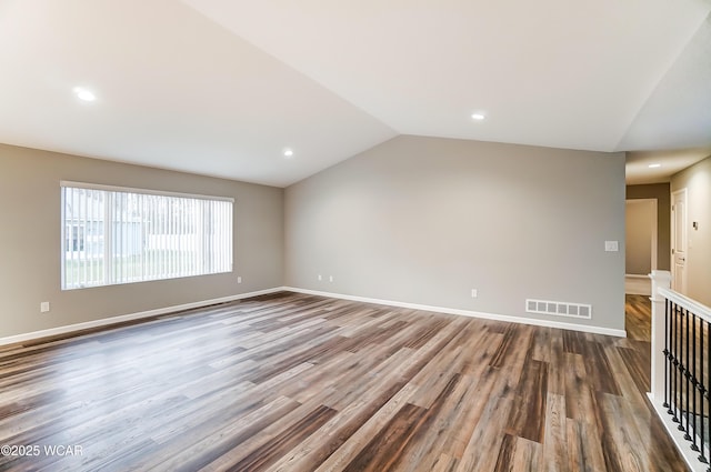 unfurnished room with lofted ceiling, wood finished floors, visible vents, and baseboards