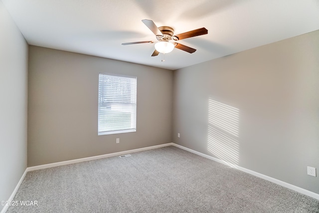 carpeted spare room featuring visible vents, a ceiling fan, and baseboards