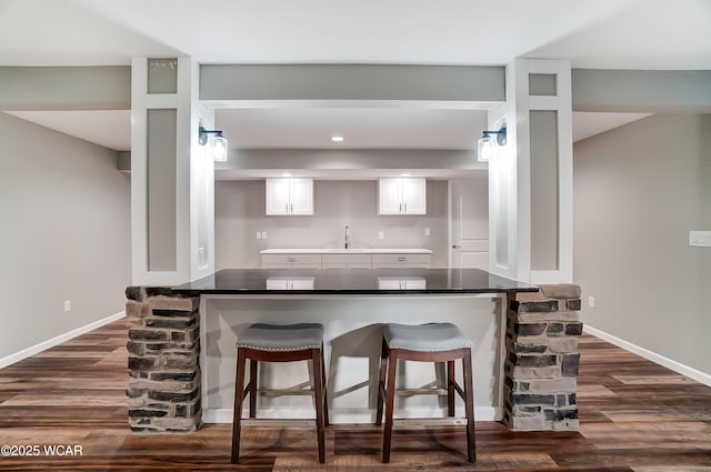 kitchen with dark countertops, white cabinets, a peninsula, and a breakfast bar area