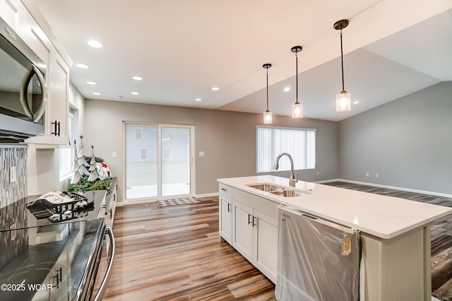 kitchen with white cabinets, dishwasher, stainless steel microwave, pendant lighting, and a sink