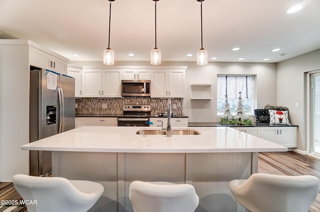 kitchen featuring dark countertops, appliances with stainless steel finishes, white cabinets, and hanging light fixtures