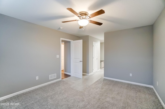 unfurnished bedroom with light carpet, a ceiling fan, visible vents, and baseboards