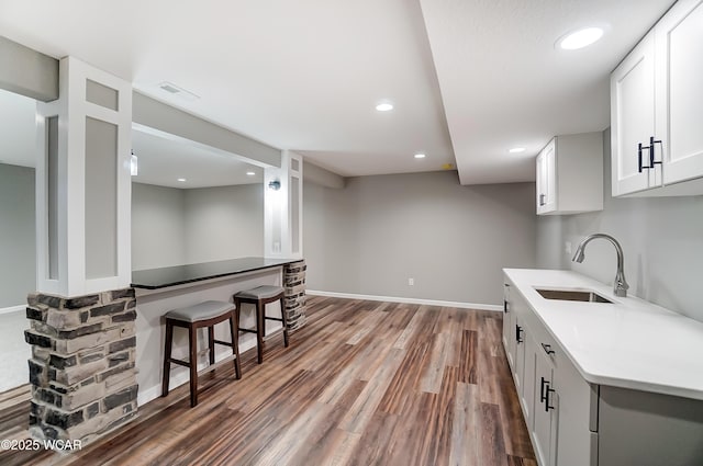 kitchen with visible vents, wood finished floors, light countertops, white cabinetry, and a sink