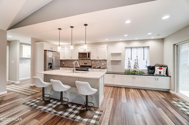 kitchen with dark countertops, decorative light fixtures, stainless steel appliances, white cabinetry, and a sink