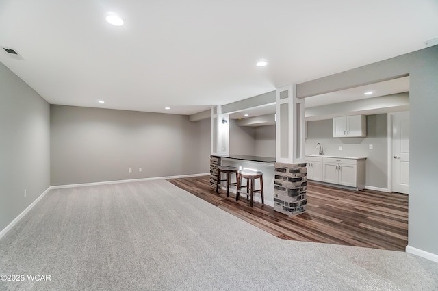 kitchen featuring recessed lighting, a sink, white cabinets, open floor plan, and light countertops