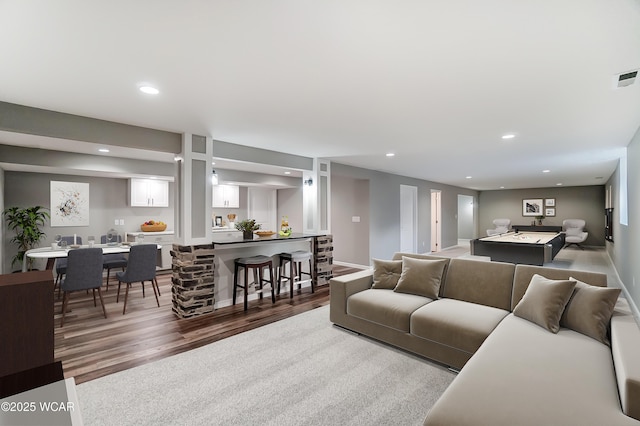 living area with recessed lighting, bar area, baseboards, and wood finished floors