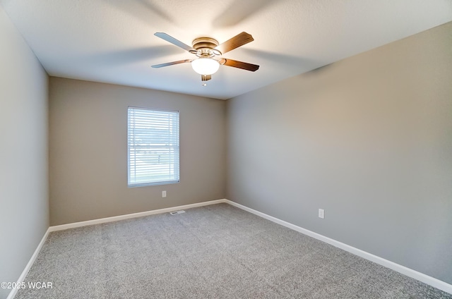 carpeted spare room with a ceiling fan and baseboards