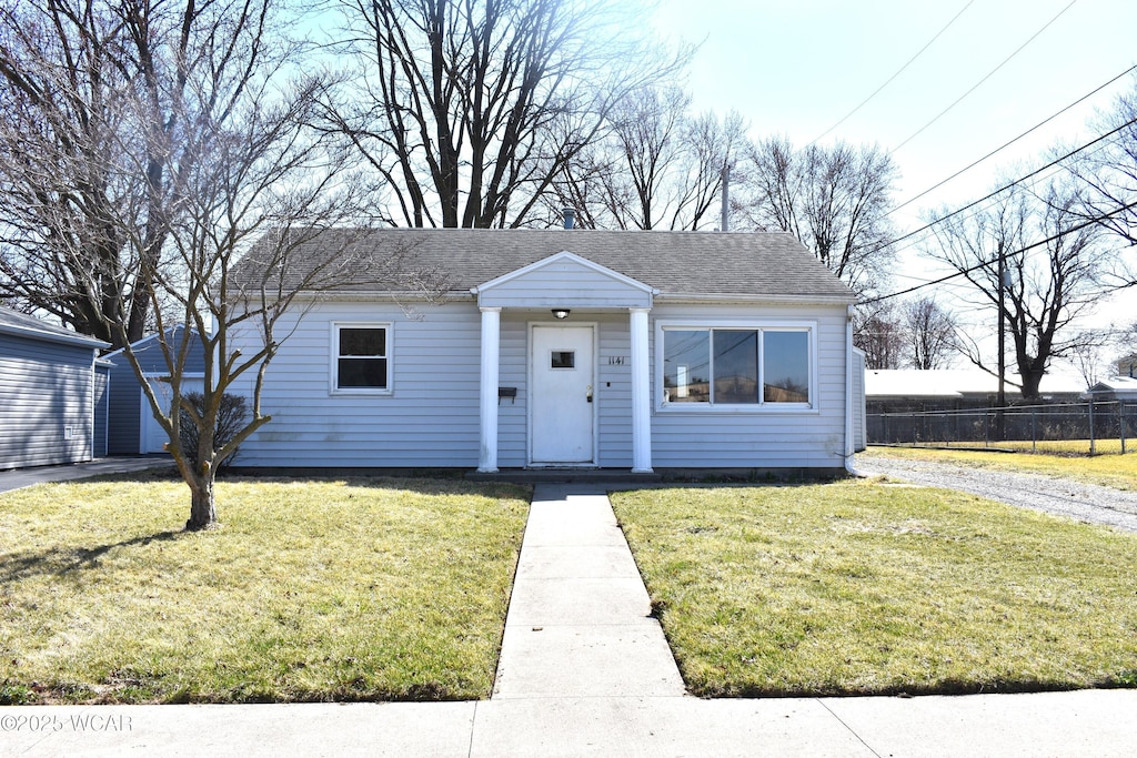 bungalow-style house with a shingled roof, a front yard, and fence