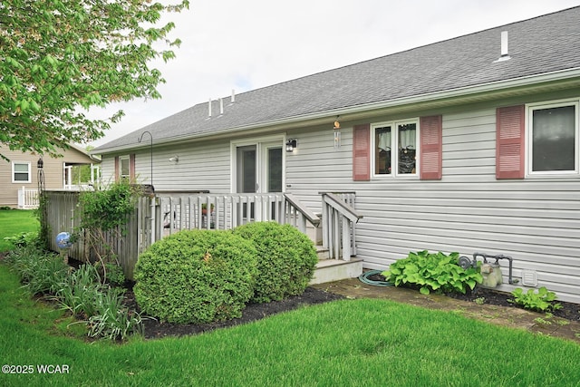 back of property featuring a yard, roof with shingles, and a wooden deck