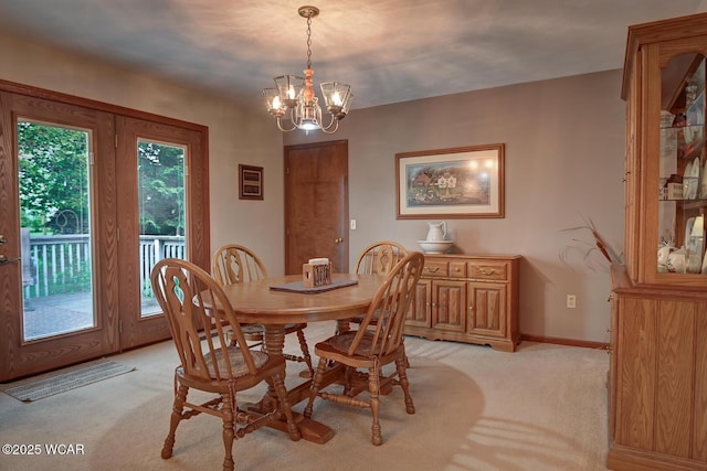 dining area featuring a chandelier, light carpet, and baseboards