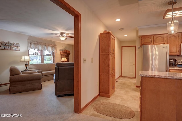 kitchen featuring freestanding refrigerator, light stone countertops, pendant lighting, recessed lighting, and baseboards