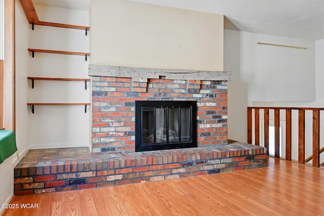 unfurnished living room with a brick fireplace and wood finished floors