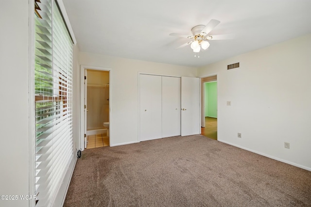 unfurnished bedroom with visible vents, baseboards, a closet, ensuite bathroom, and carpet