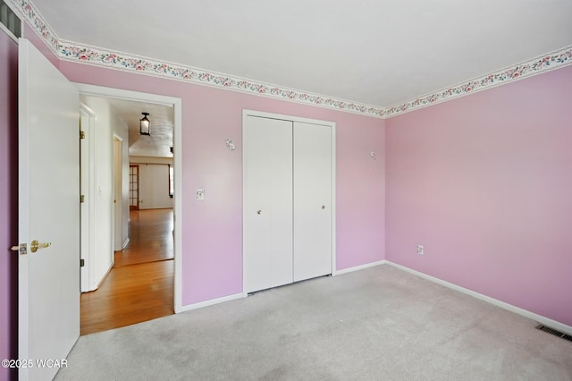 unfurnished bedroom with a closet, baseboards, carpet flooring, and visible vents