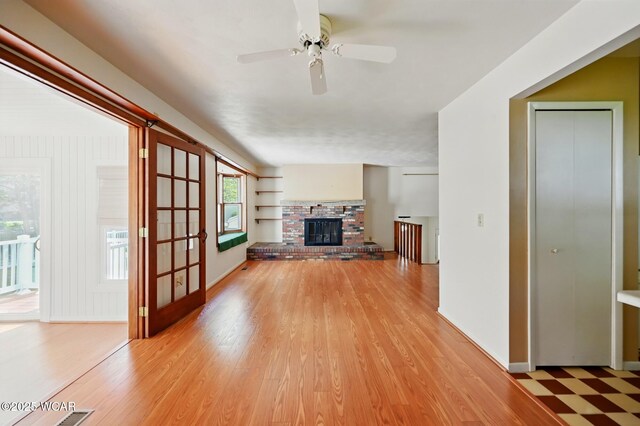 unfurnished living room featuring a ceiling fan, baseboards, light wood-type flooring, and a fireplace