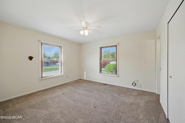 carpeted empty room with baseboards, ceiling fan, and a healthy amount of sunlight