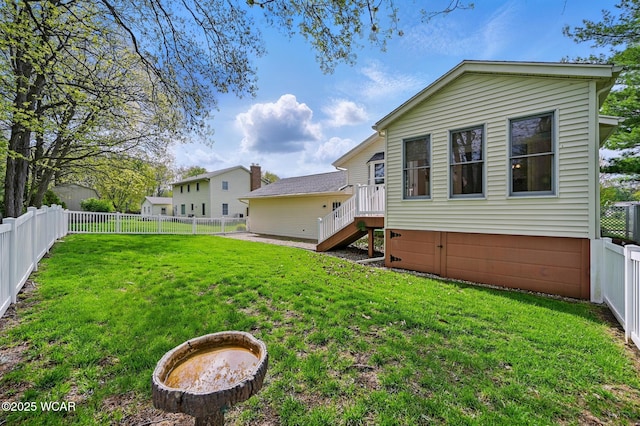 rear view of house featuring a yard and a fenced backyard