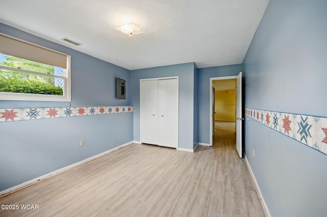 unfurnished bedroom featuring visible vents, a closet, wood finished floors, baseboards, and electric panel