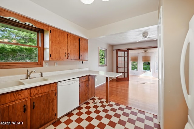 kitchen featuring a sink, white appliances, light countertops, a ceiling fan, and light floors