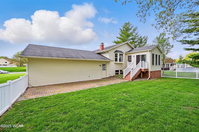 back of property with a lawn, a fenced backyard, a sunroom, and a shingled roof