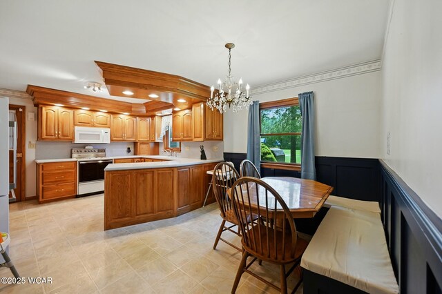 1317 Melrose St, Lima, OH 45801 - kitchen featuring white appliances, a chandelier, light countertops, brown cabinetry, and a peninsula