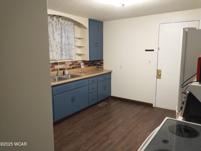 kitchen with blue cabinets, dark wood-style flooring, a sink, light countertops, and open shelves